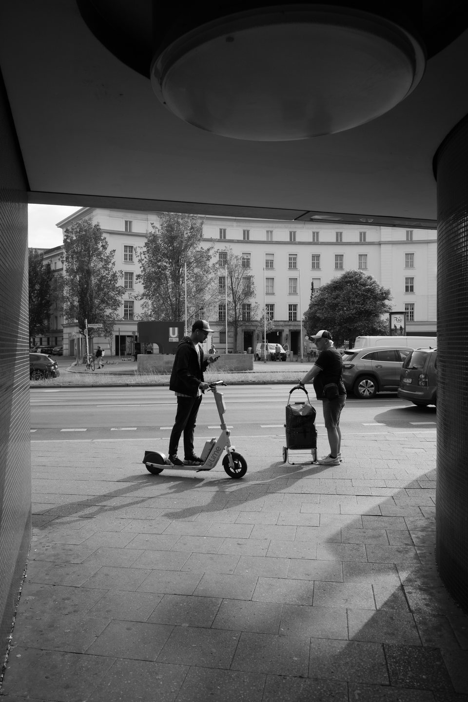 An electric scooter rider crossing a sunlit street