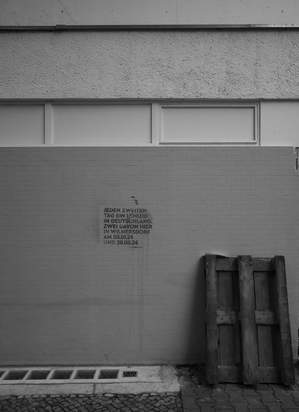 A pale wall with a small inscription and stacked barriers