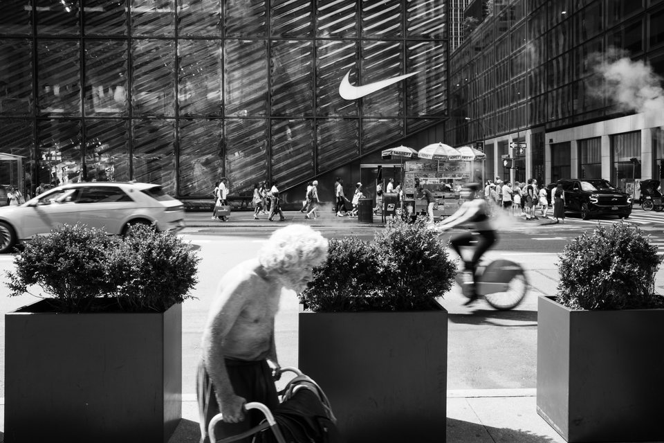 A cyclist passing storefront windows behind concrete planters