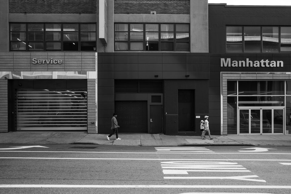 A lone pedestrian passing a commercial facade marked Manhattan