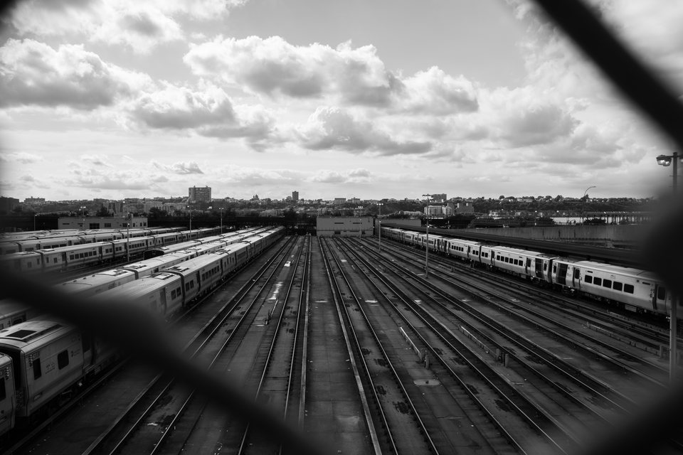 Railway tracks and parked trains viewed through a fence