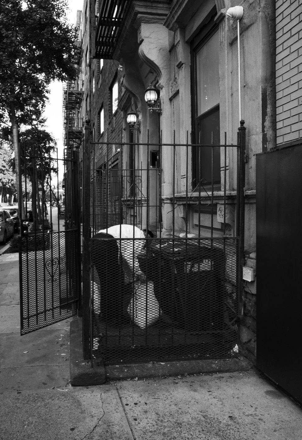 A person bending down behind an iron fence beside a townhouse