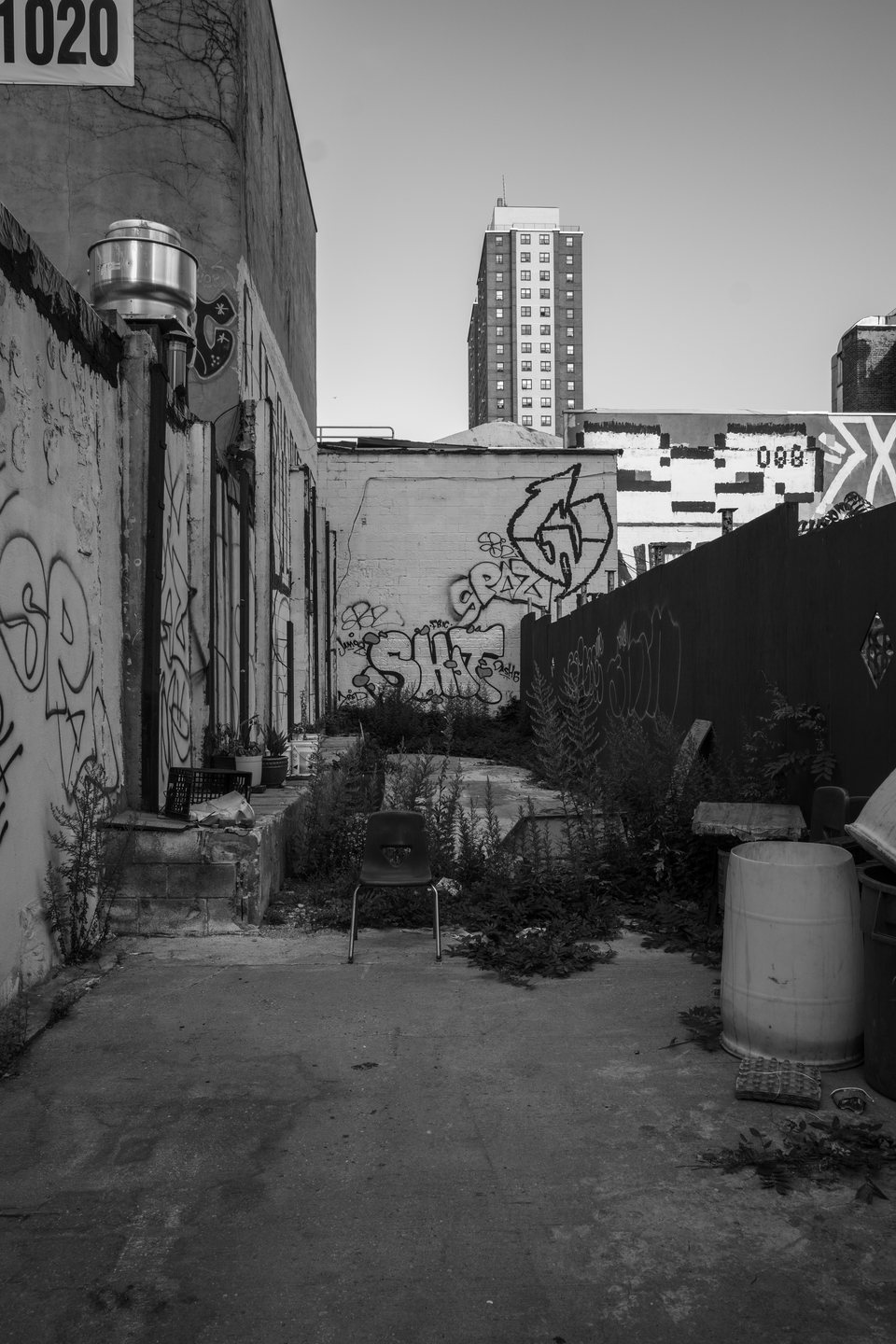 A graffiti-covered vacant lot with a high-rise beyond it