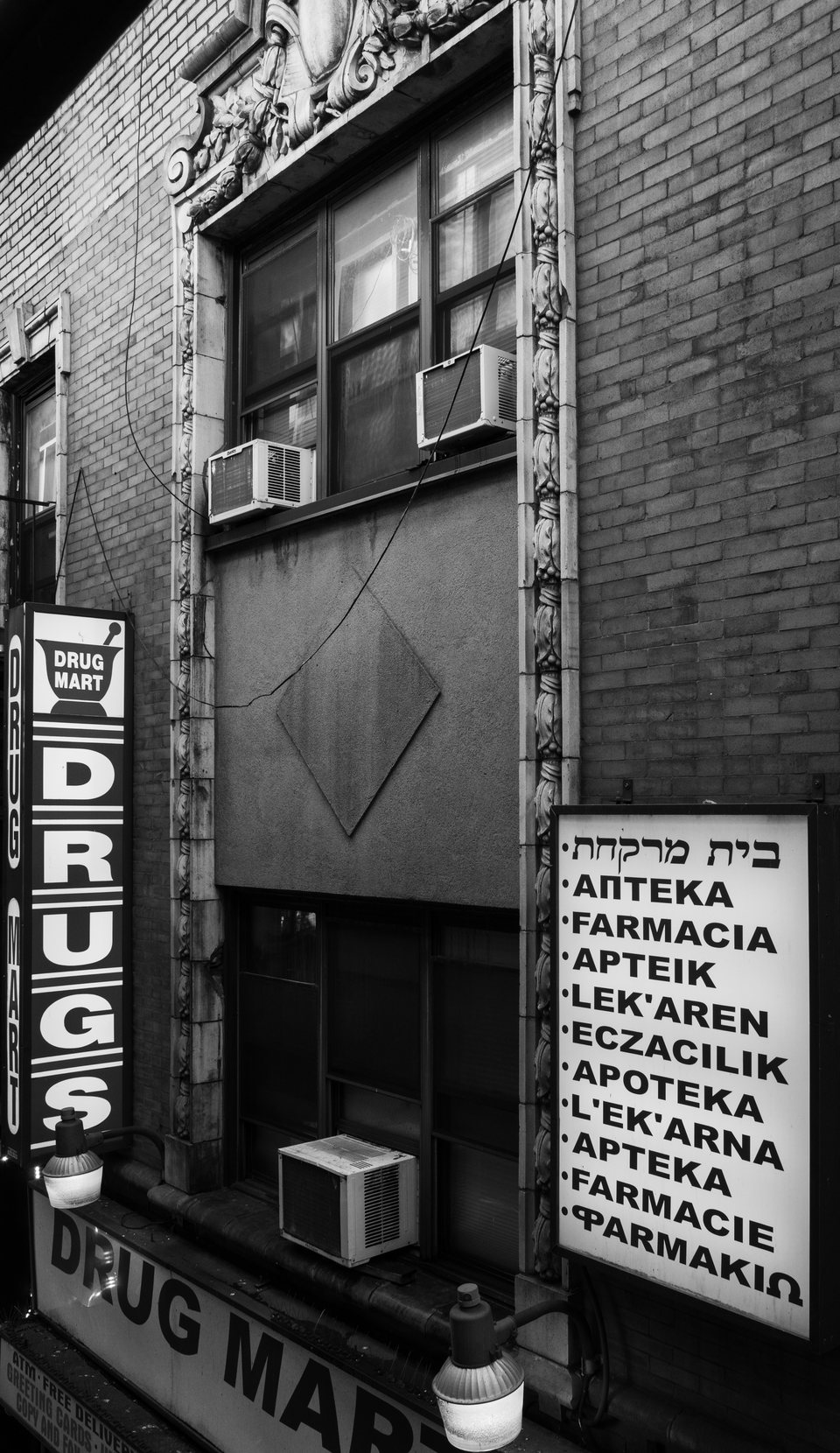 Vertical pharmacy signs in several languages on a brick building