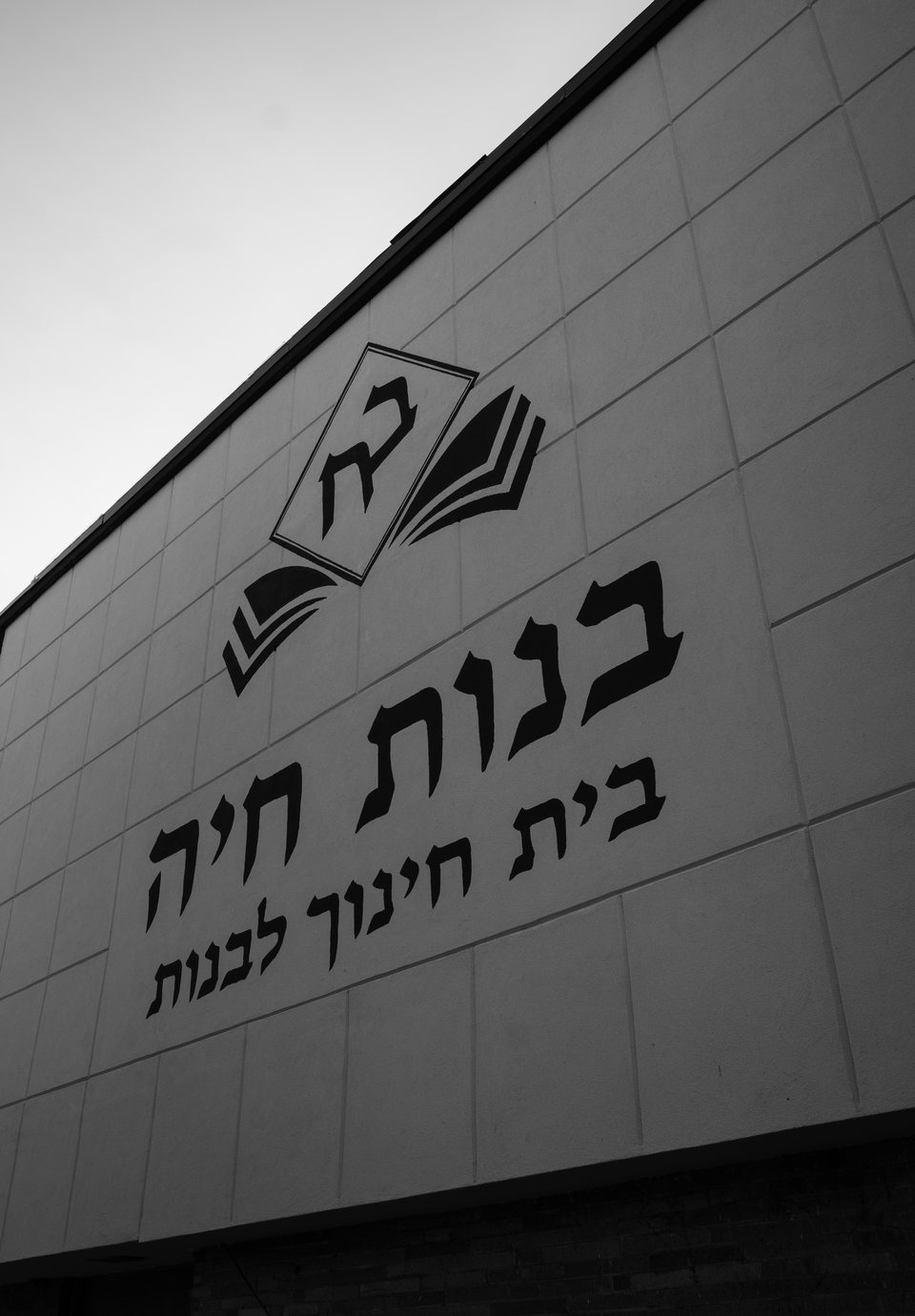 Hebrew lettering and an open-book emblem on a school facade