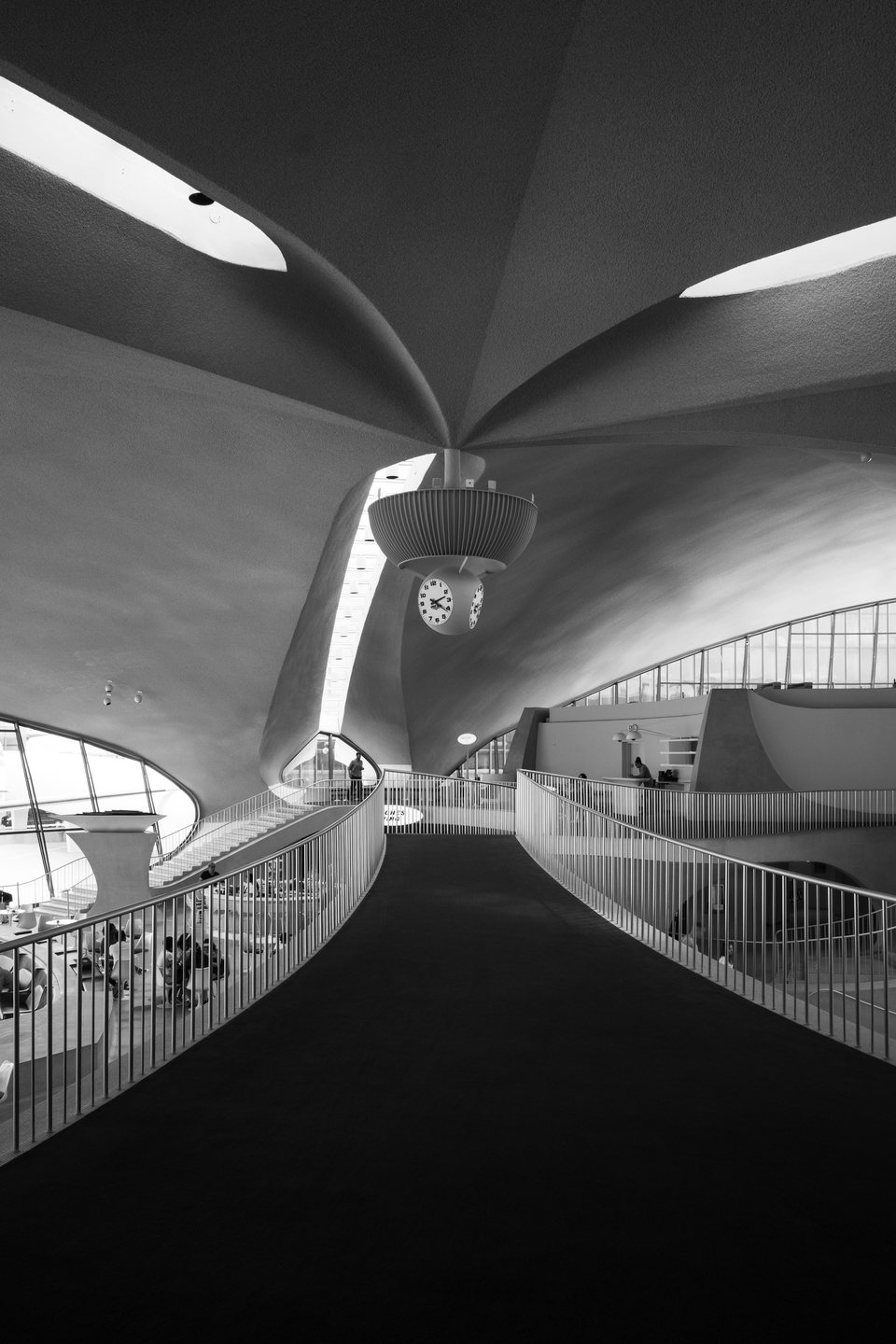 A dark carpeted ramp rising through the white interior of the TWA Flight Center